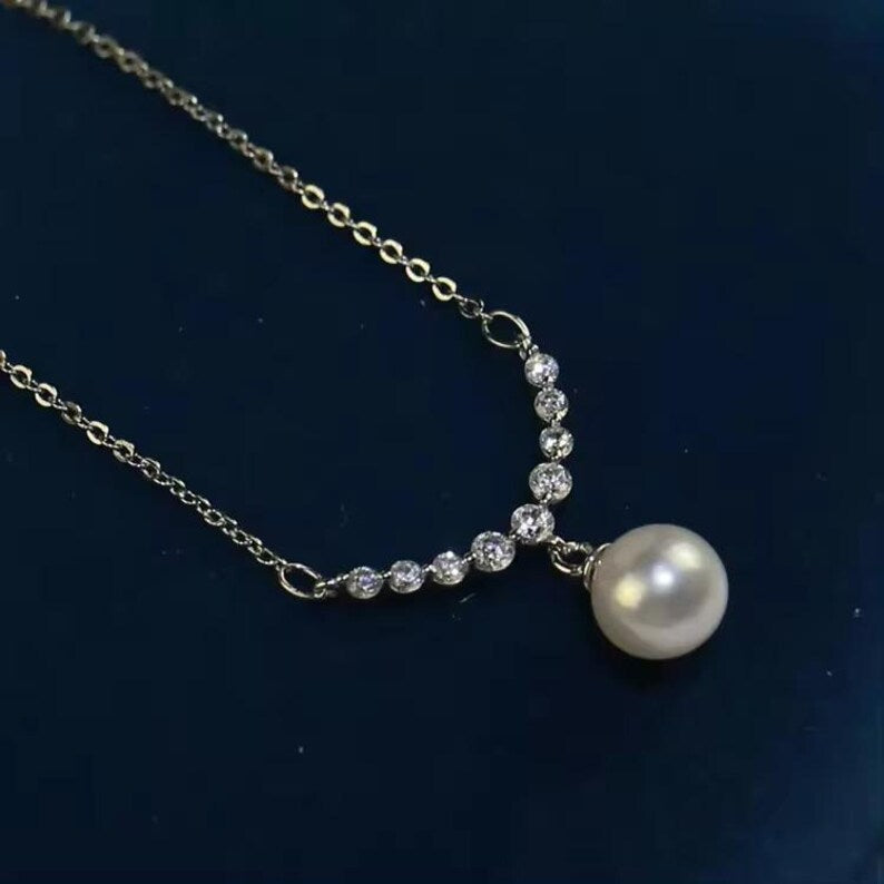Close-up of freshwater pearl pendant surrounded by sparkling round zircon stones on a silver chain.”