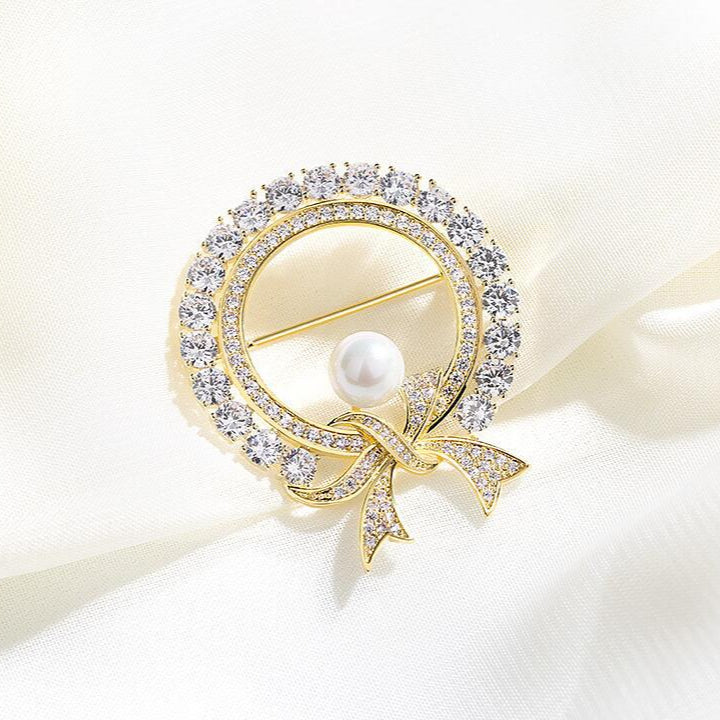 Gold circle brooch with crystal bow and pearl center

