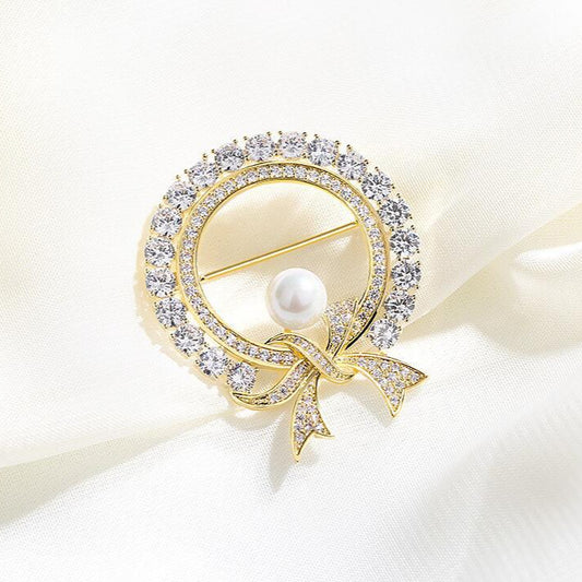 Gold circle brooch with crystal bow and pearl center

