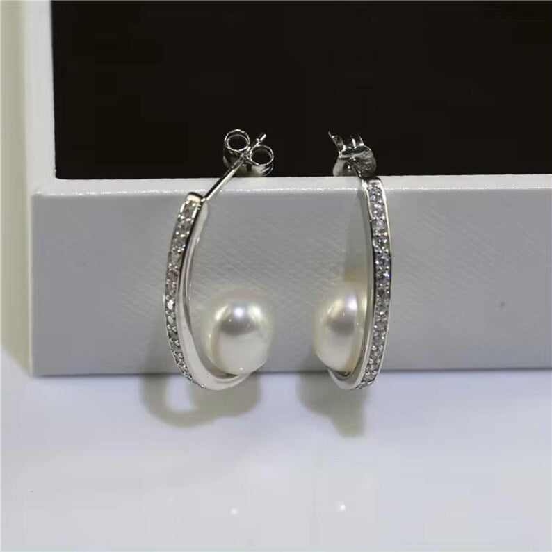 Silver hoop earrings with pearls on a white surface